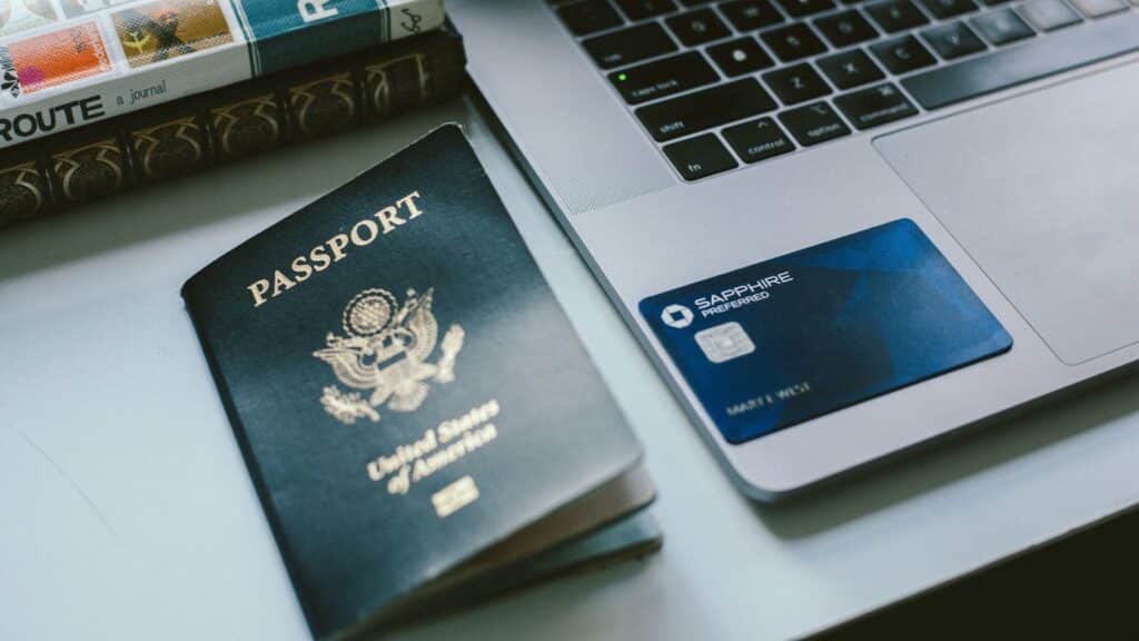 A Chase Sapphire preferred card sits on the edge of a laptop next to a United States passport