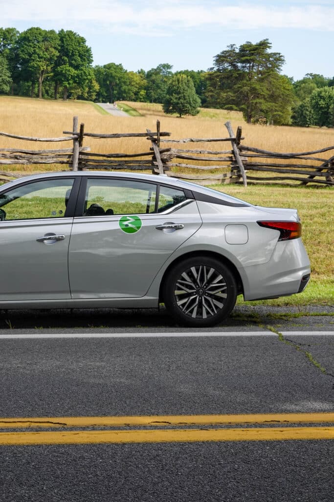 Zipcar parked along a roadside next to an early American Virginia fence